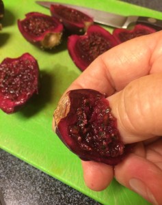 Scooping out seeds from prickly pear fruit cut in half 
