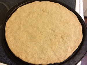 Pizza dough risen and kneaded then stretched and patted out on pizza pan ready for toppings
